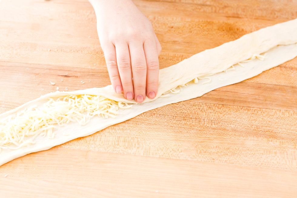 Fold the dough over the cheese, pressing down to seal. We rolled ours too to ensure it was a tight seal.