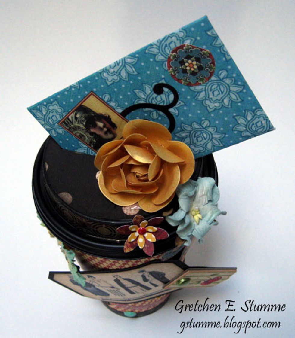 16.\tSecure lid to cup, slip gift card envelope into slit in lid, at an angle, and decorate cup as desired.