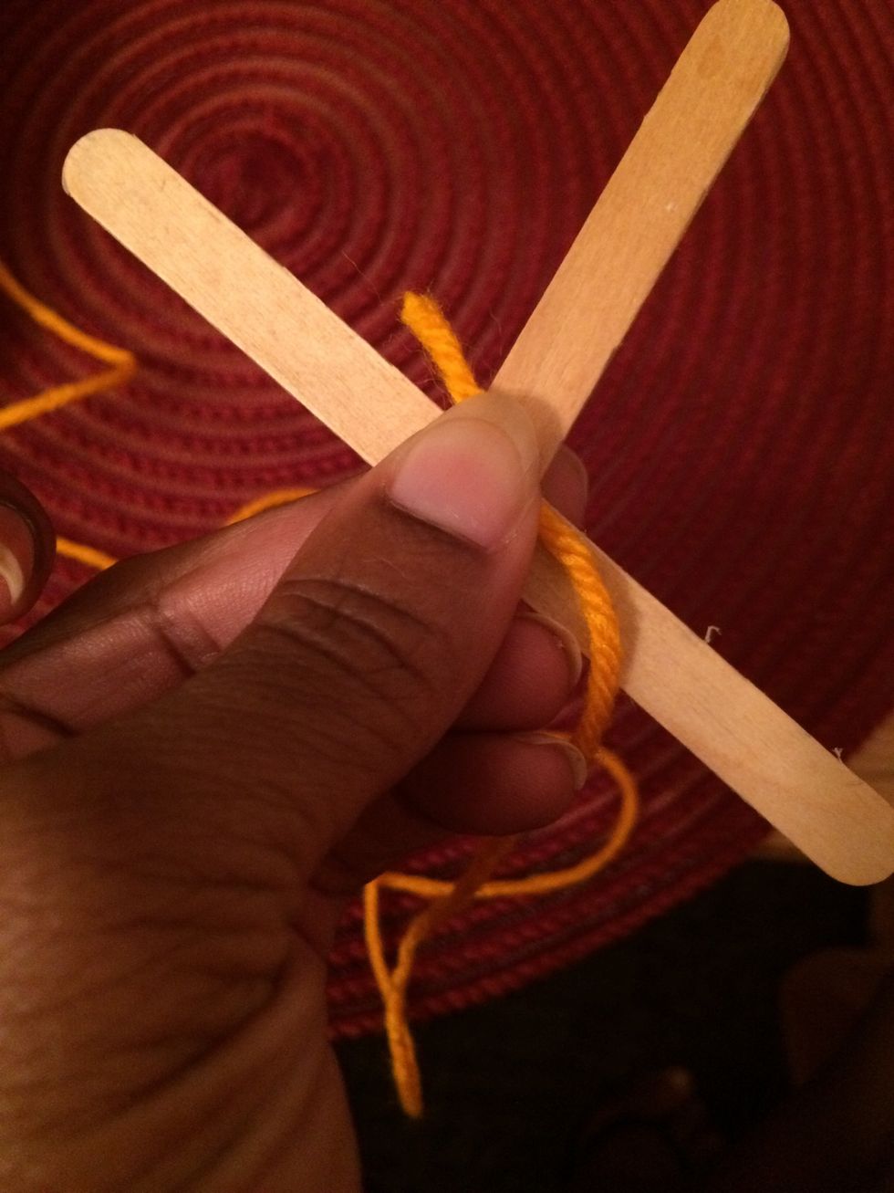 3. Position your yarn in the center of the sticks. We will use the yarn to secure the sticks.