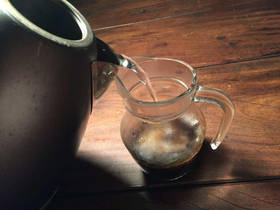 3)Pour hot water into the jug in order to dissolve the coffee. As you pour it in you will see the ground coffee will disappear and turns into a liquid substance.