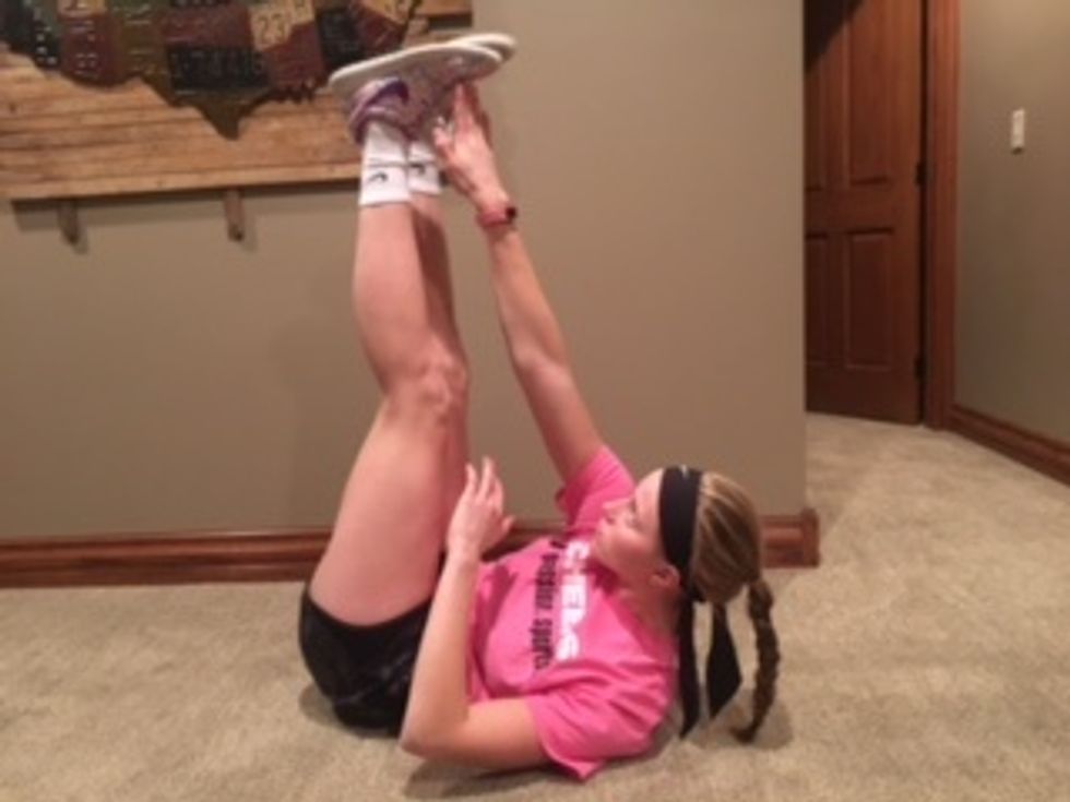 3. Toe Touches- Lie on the ground with legs extended upwards. Reach with your right hand to touch your opposite leg's foot. Repeat with the left hand. Do 15 reps each side.