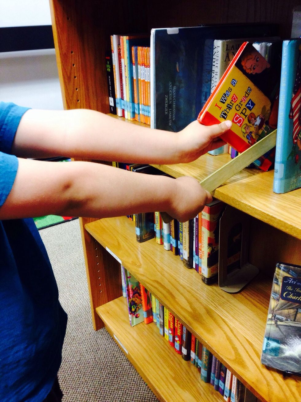 3. You may browse the shelves to look for a good fit book. Place your shelf marker next to a book that looks good to you, and take the book off the shelf.