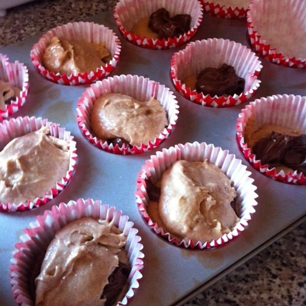 5. Line a muffin tray with cases. 6. Put in a tablespoon of batter into each of the cases, then top with a spoon of Nutella, then cover with another spoon of batter. Like so;