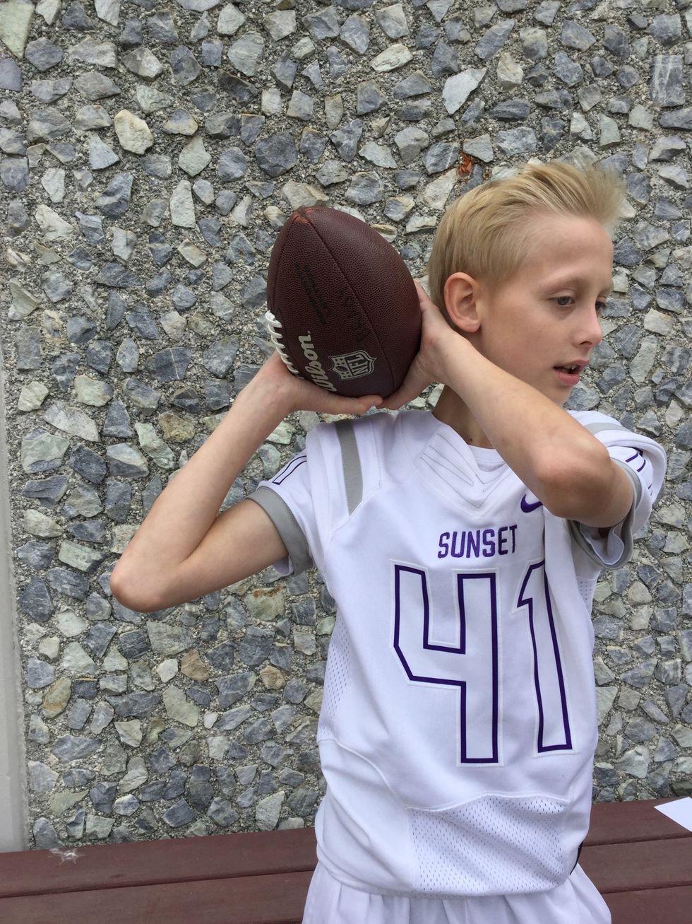 5. Put your off hand next to your other hand on the ball and put the ball behind your ear.