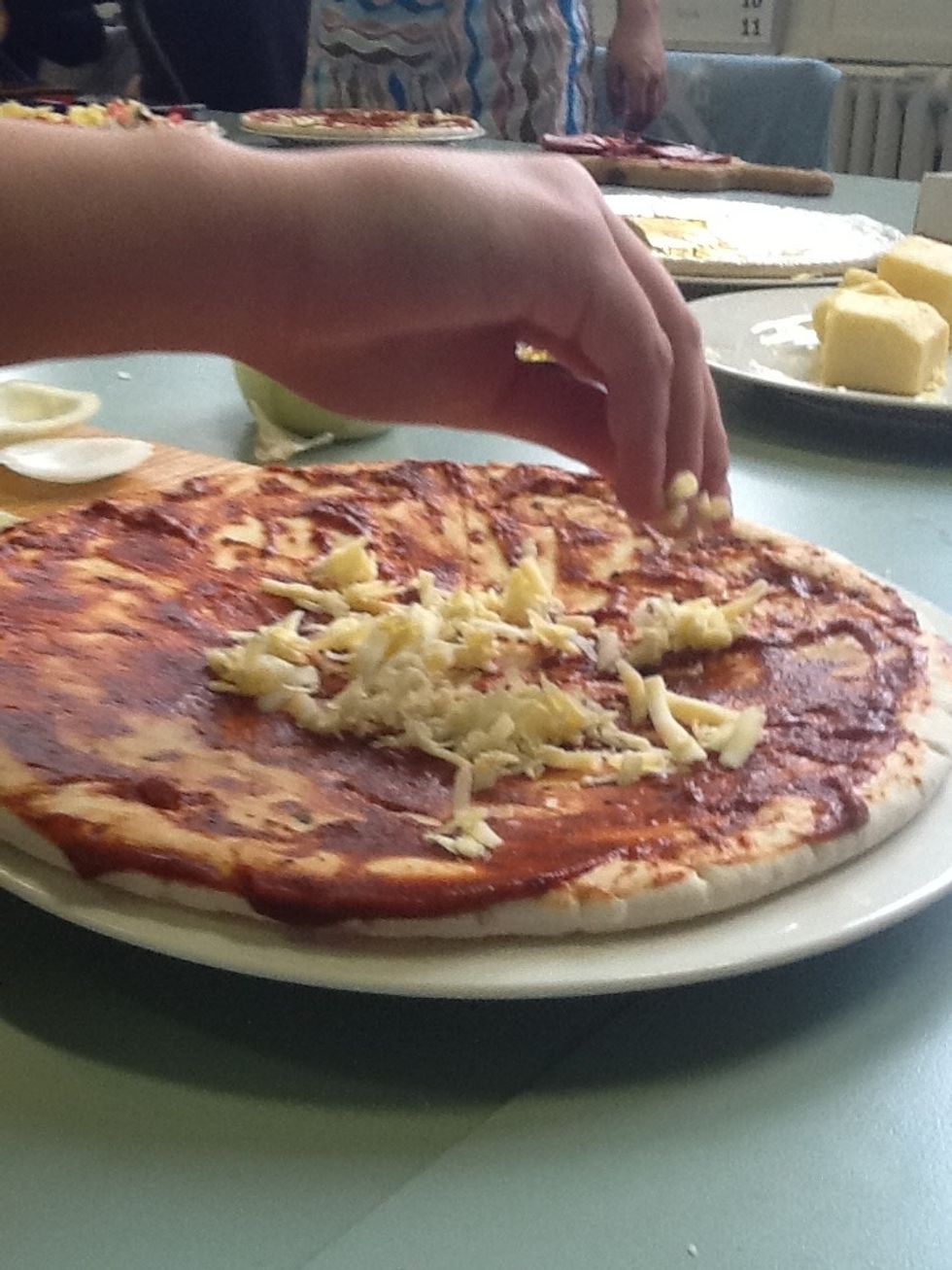 (8)Sprinkle the cheese on the pizza base.
