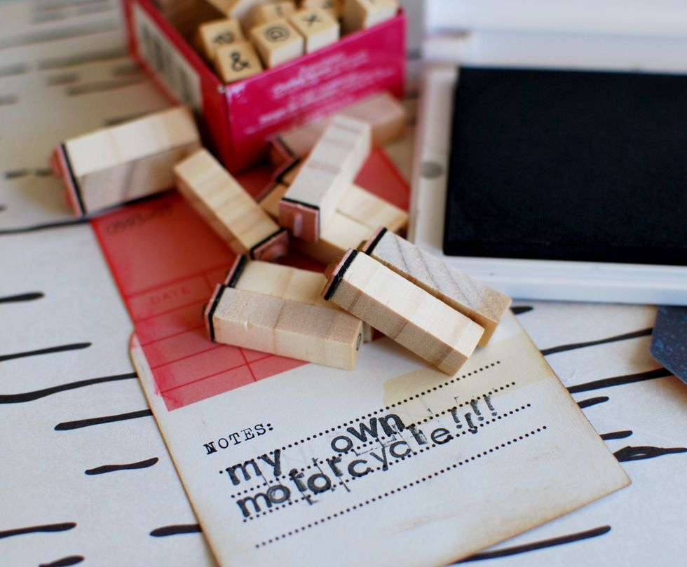 8.\tUse alphabet stamps and black ink to add a title on the date card.  9.\tInk the edges of the card.  10.\tWith your marker, add the date on the upper red area of the card.
