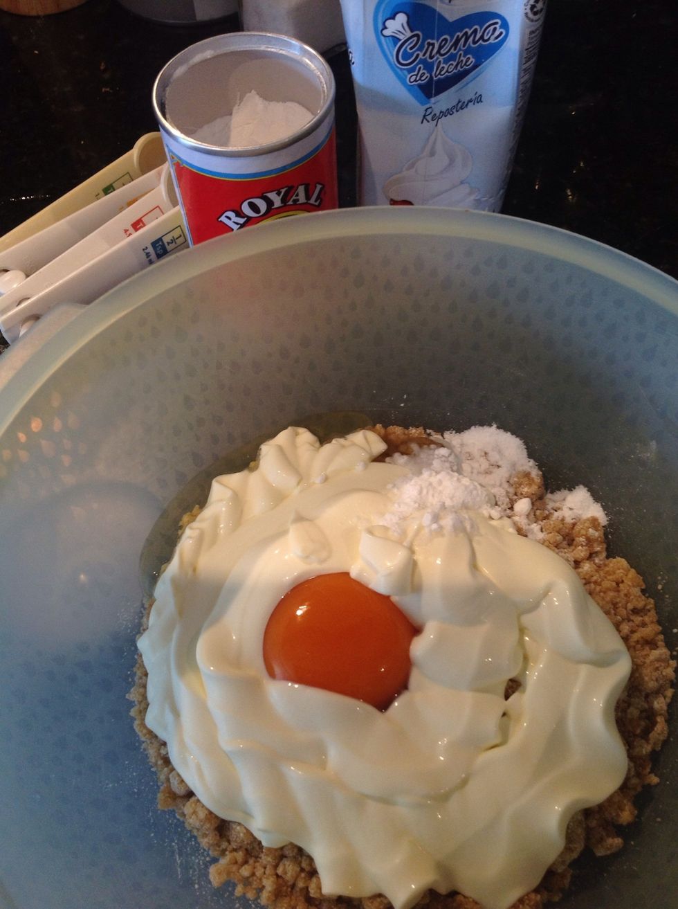 A la mezcla restante de azucar, harina y mantequilla, a\u00f1ade el huevo, la crema de leche y el polvo de hornear. Mezcla todo muy bien con un tenedor.