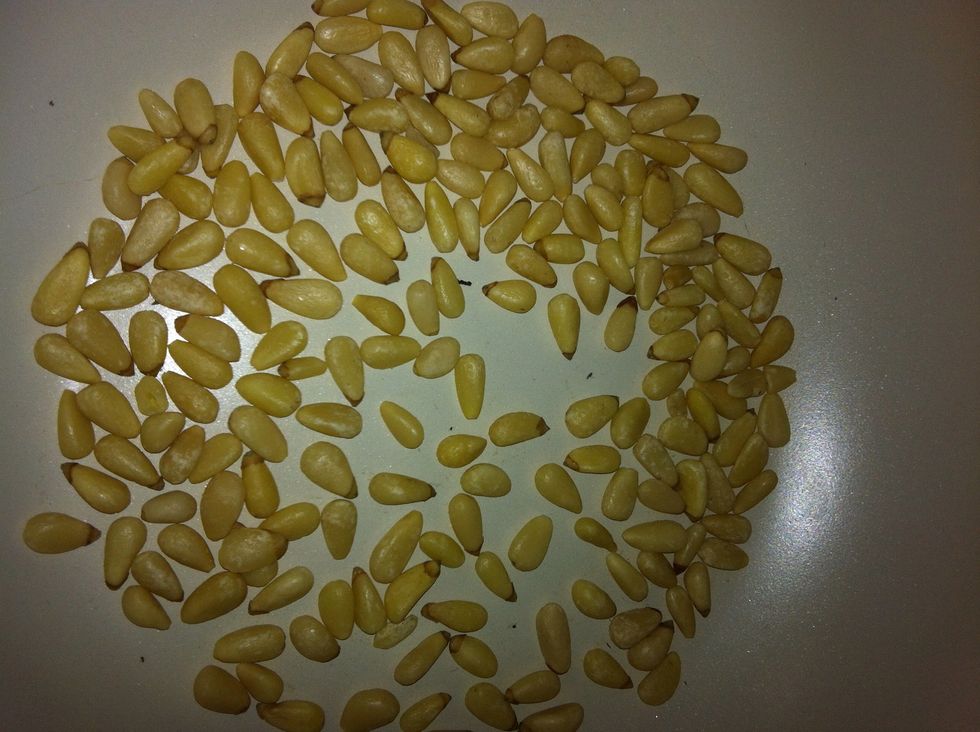 A palmful of pine nuts.. For more flavor you can toast these guys in a pan. But be very careful, they burn very easily. Lightly toast them to brown a bit. Don't worry if some burn a little bit.