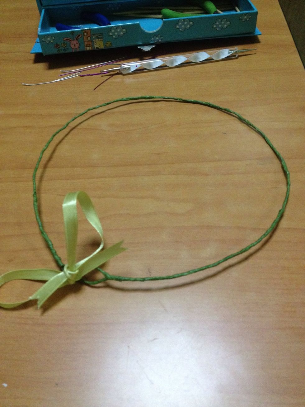 a ribbon which is tied through the loops at both ends. The ribbon can add to the circumference of the wreath. Cover the wreath with green tape as well :)