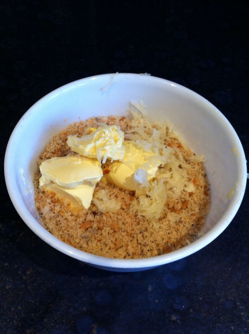 Add 2 and a half tablespoons of butter OR margarine (whichever you prefer) into the bowl of breadcrumbs. Crush 3 garlic cloves and add to the mixture... Stir well so it all mixes together evenly