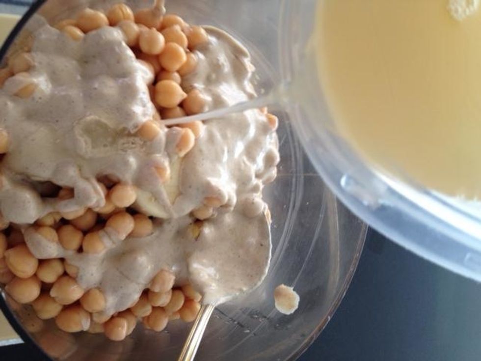 Add 2 cans of drained garbanzo beans to food processor. Add in tahini sauce (about 1/2-3/4 C), garlic, cumin, salt, lemon juice, about 1/3 C water and process. Stop and taste test. Process till silky.