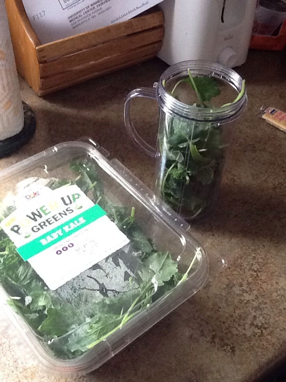Add 2 cups of kale to your blender (I'm using a Magic Bullet). Kale has a mild flavor and is packed with nutrients.