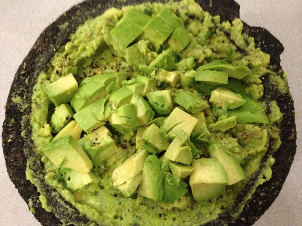 Add 2 remaining chopped avocados to the mixture. Squeeze 1/2 lime on top of avocado mixture. Gently mash with molcajete stone or a fork, leaving chunks of avocado.