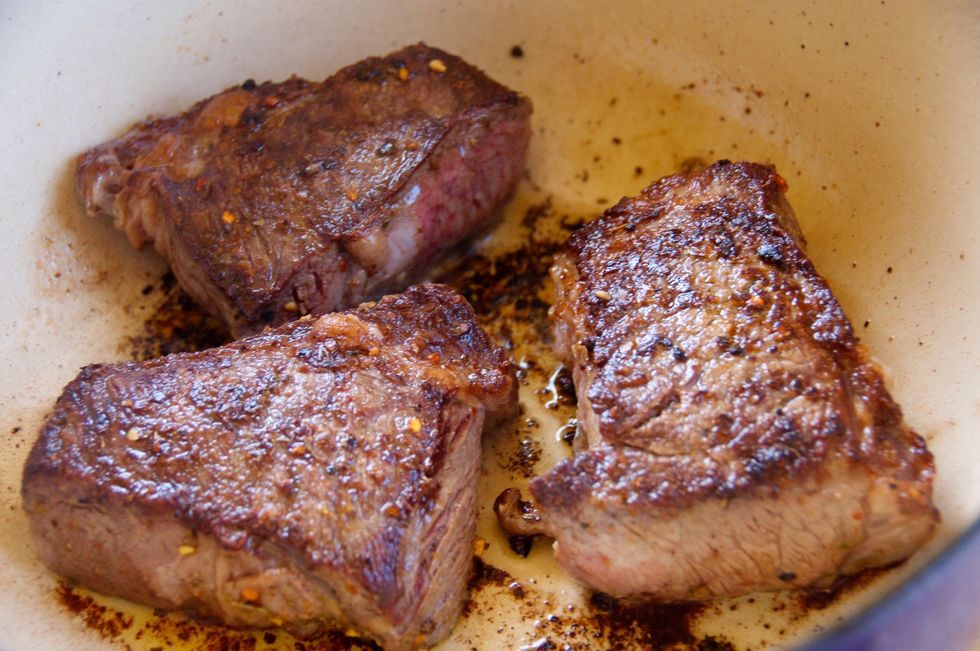 Add 2 TBSP of olive oil to your dutch oven and place over high heat. Make sure the oil is hot enough to hear a sizzle when you brown the rib meat.  Cook 3-5 minutes per side until well browned...