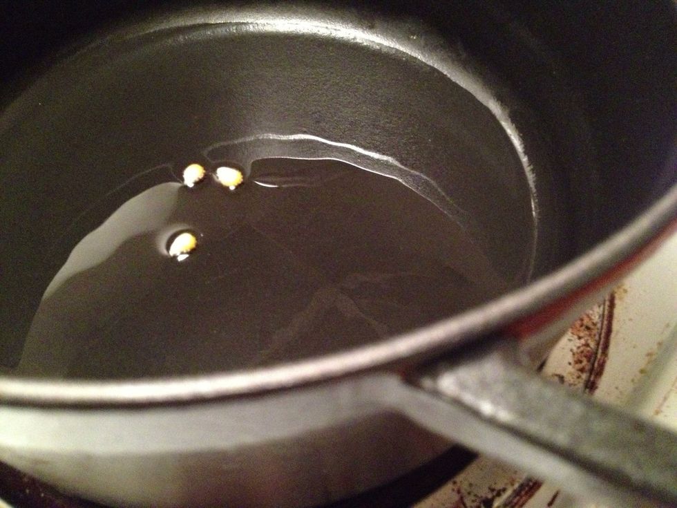 Add 3-4 kernels of corn to the pot and cover. This will serve as a timer to let you know when the oil has reached the right temperature to cook the popcorn evenly.