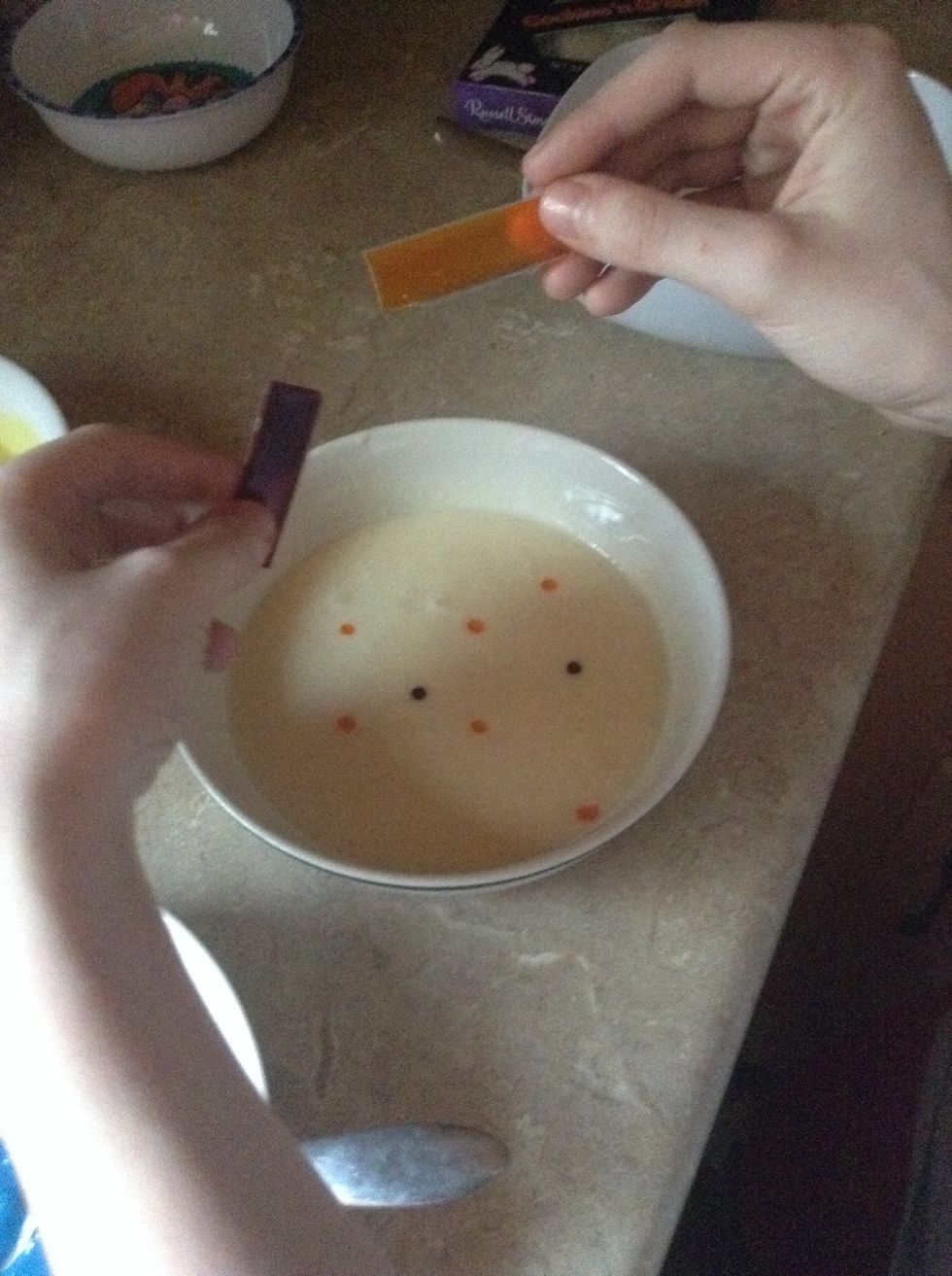 Add 5 drops of yellow and 2 drops of red dye to make orange in another bowl and stir