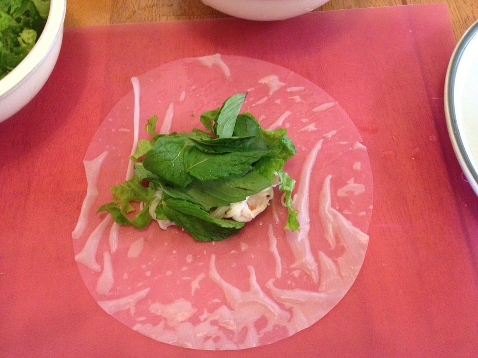 Add a bit of lettuce, 3 mint leaves and 3 basil leaves. A sprig of cilantro goes here too. Then carefully roll them up like an egg roll or burrito.