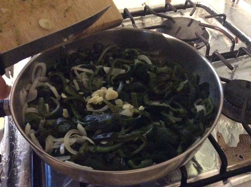 Add a clove of garlic to the chilies and onion.