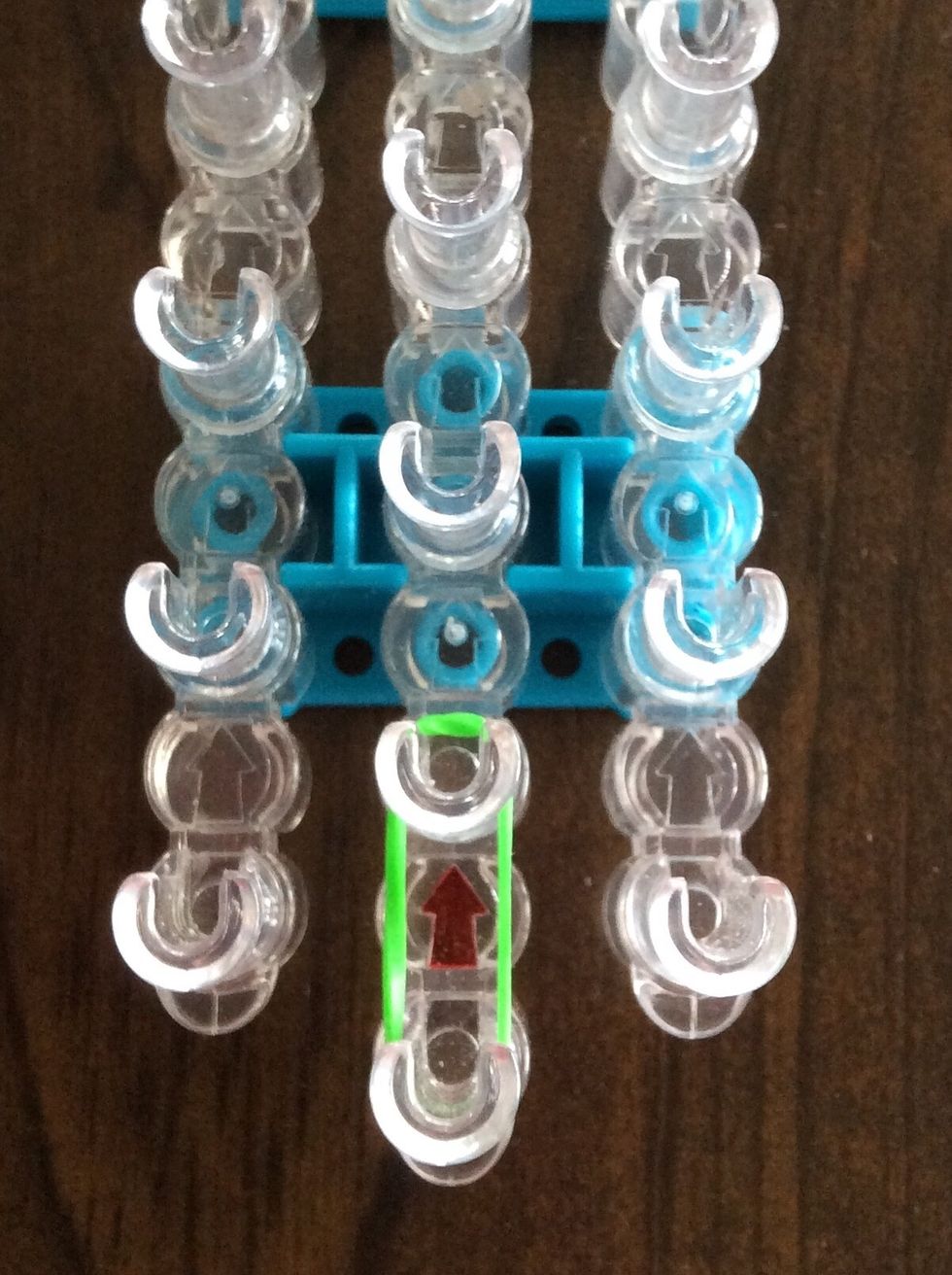 Add a green band from the first middle peg to the second middle peg.