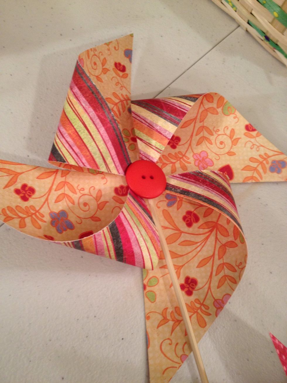 Add a large button to the center with another glut dot. Want it to spin? Overlap all four corners in center, punch hole.. Attach with brad. Add skewer to back of brad with glue dot.