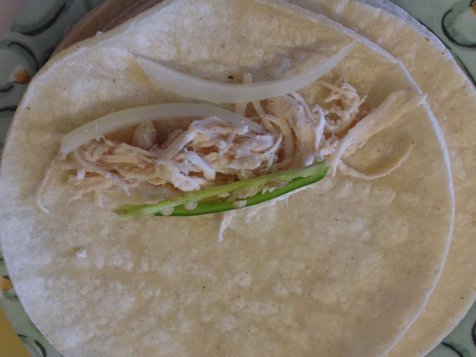 Add a little bit of chicken, a slice of serrano pepper, and 2 slices of onion. More or less, to your liking. You can also omit if you don't want either. I like the extra spicy kick. Roll it up.