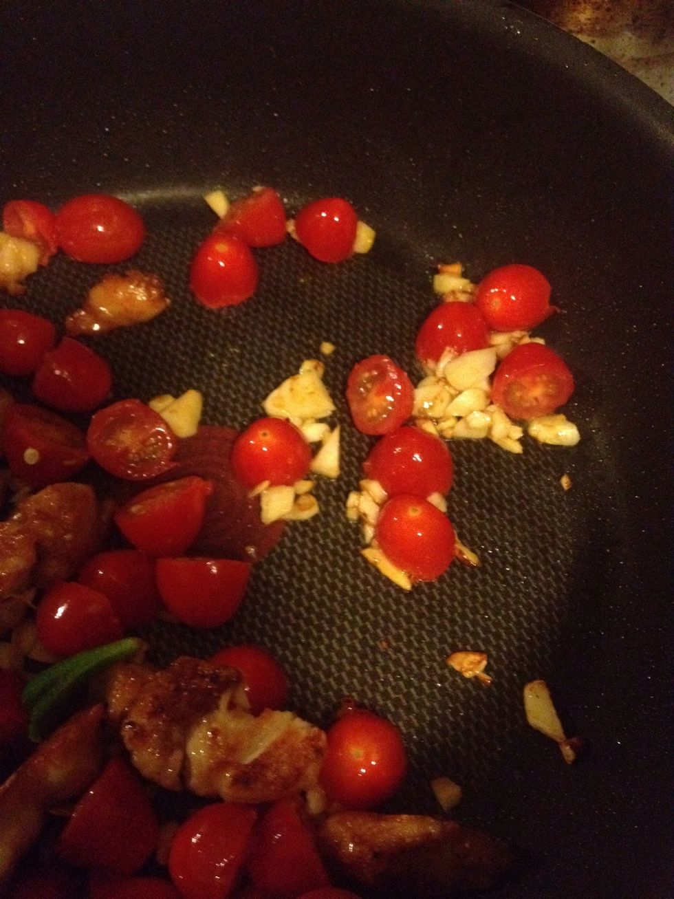 Add a little bit of oil, and add garlic and tomatoes.