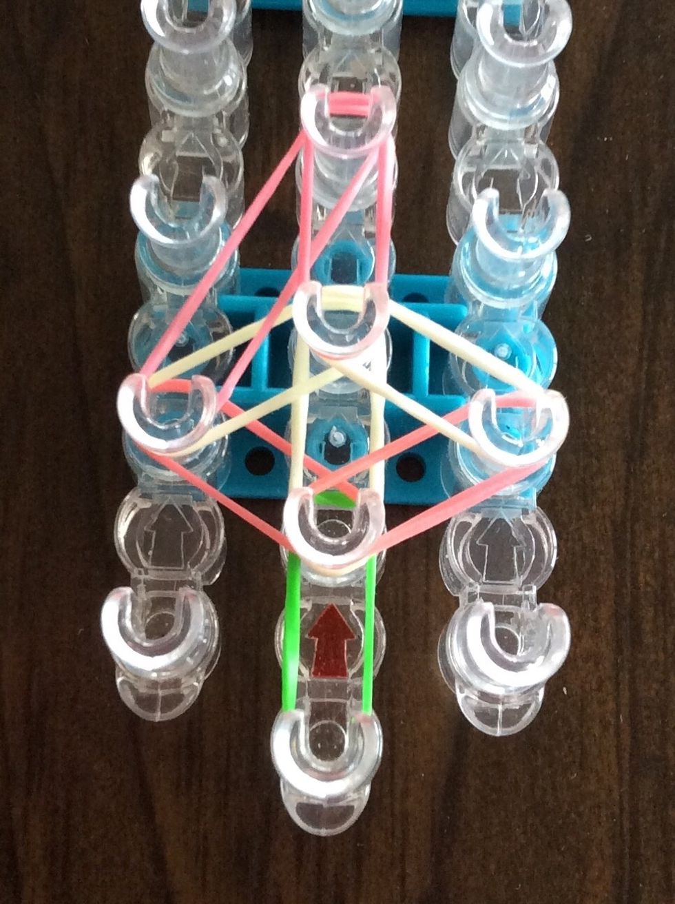Add a pink band from the third middle peg to the fourth middle peg.