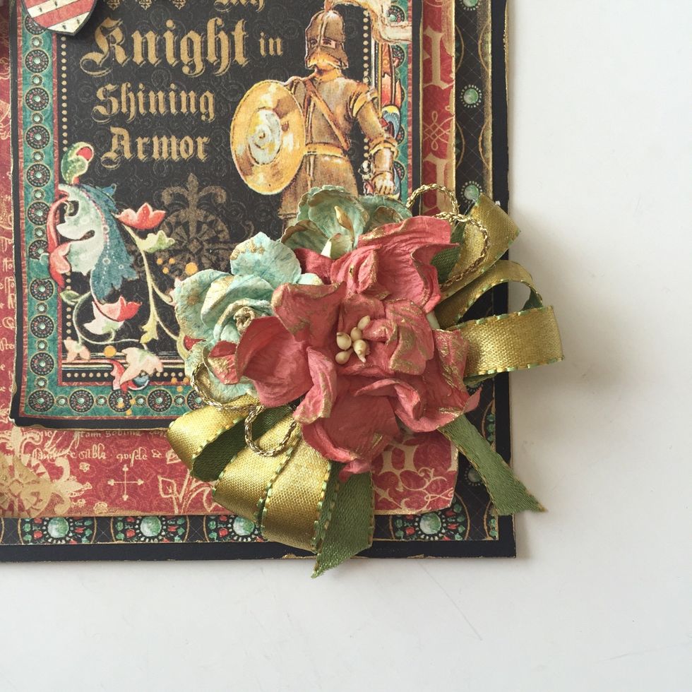 Add a ribbon bow to bottom right corner of card and layer w/ another bow of gold string. Layer with paper flowers. Add dabs of gold paint to flowers.