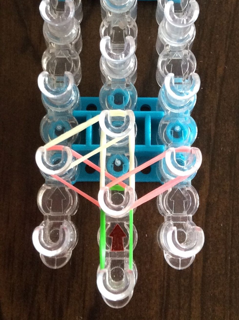 Add a white band from the second left peg to the third middle peg.