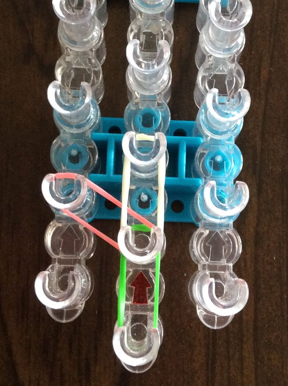 Add a white band from the second middle peg to the third middle peg.