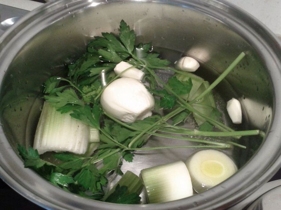 Add about 1.5 liters of water to pot. Add the cut leek and celery pieces, and the parsley, peppercorn, onion, pinch of salt and garlic. Bring to boil.