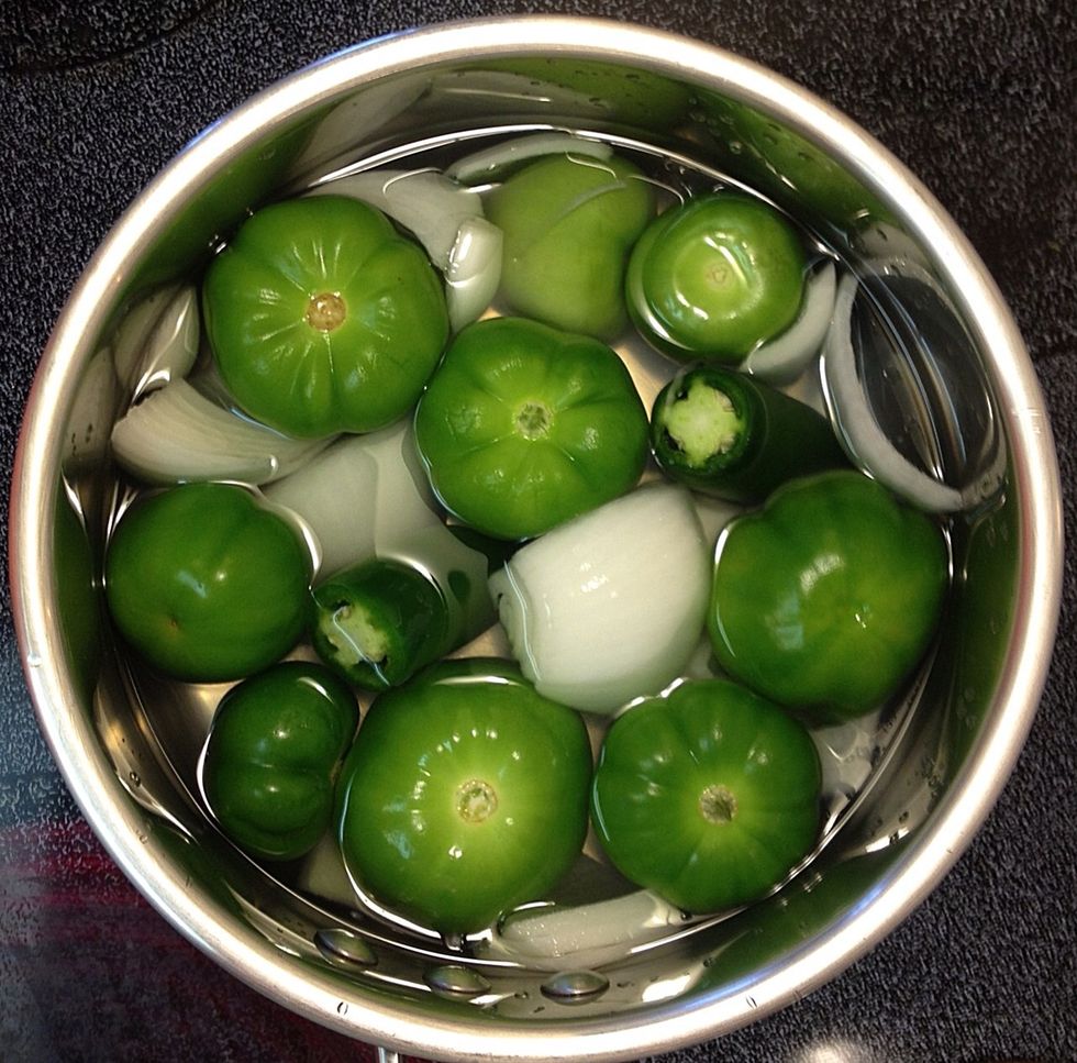 Add about 6 tomatillos, 2 jalape\u00f1os (medium heat), and 1 white onion cut into large chunks to a saucepan. Cover with water and boil until tomatillos change color (they will be grayish greenish brown).