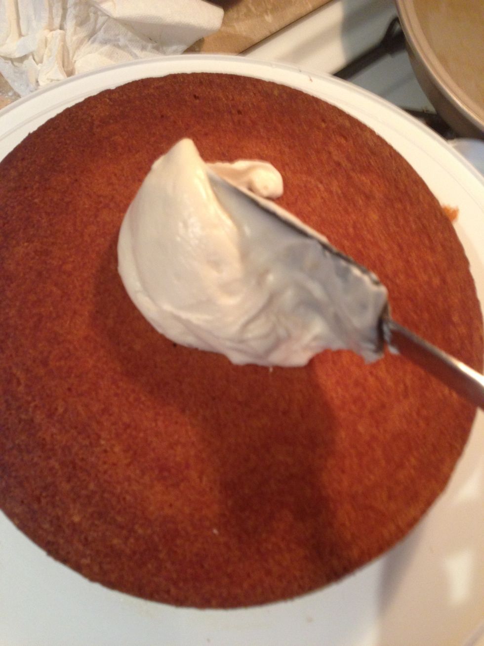 Add and smooth around frosting on the second layer of the cake's surface.