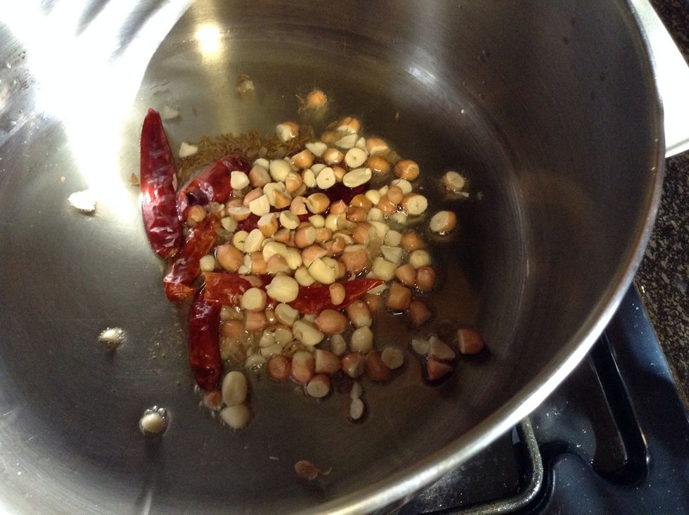 Add asafetida, red chillies, peanuts. Stir until peanuts are lightly golden brown