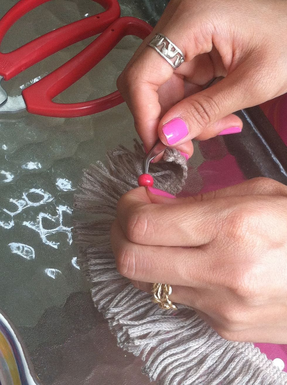 Add beads to the fringe using tweezers. Tip: use water to wet the ends of the fringe so it is easier to bead