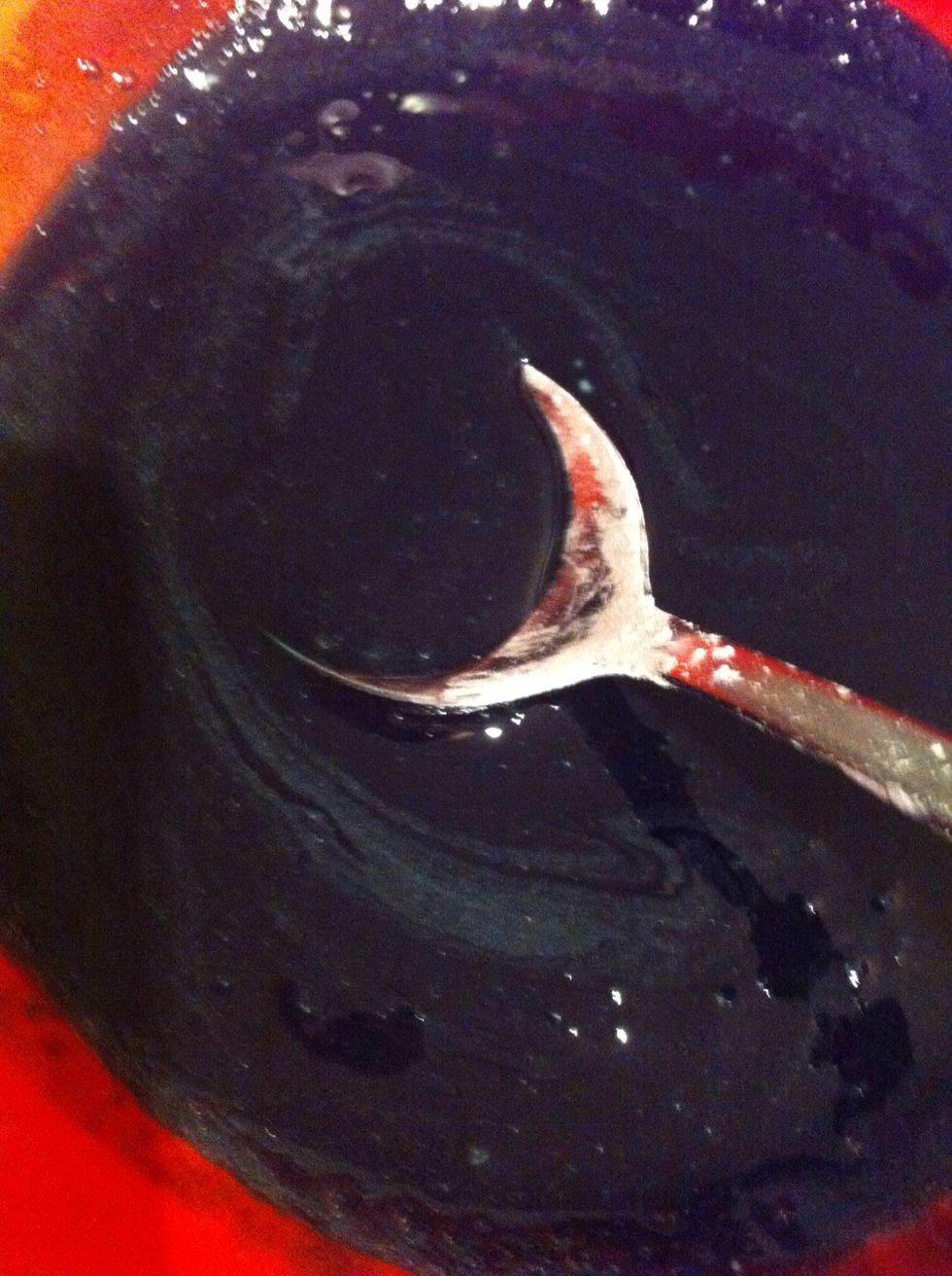 Add black food colouring to one bowl