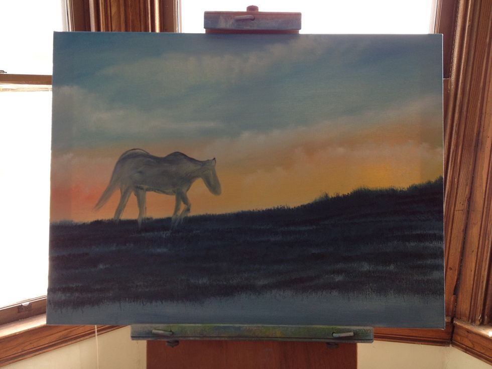 Add blue, black, and crimson to your largest chip brush and block out the land. Then varying amounts of dark on the brush and dab the darker spots in, indicating grass. Block in your horse shape.