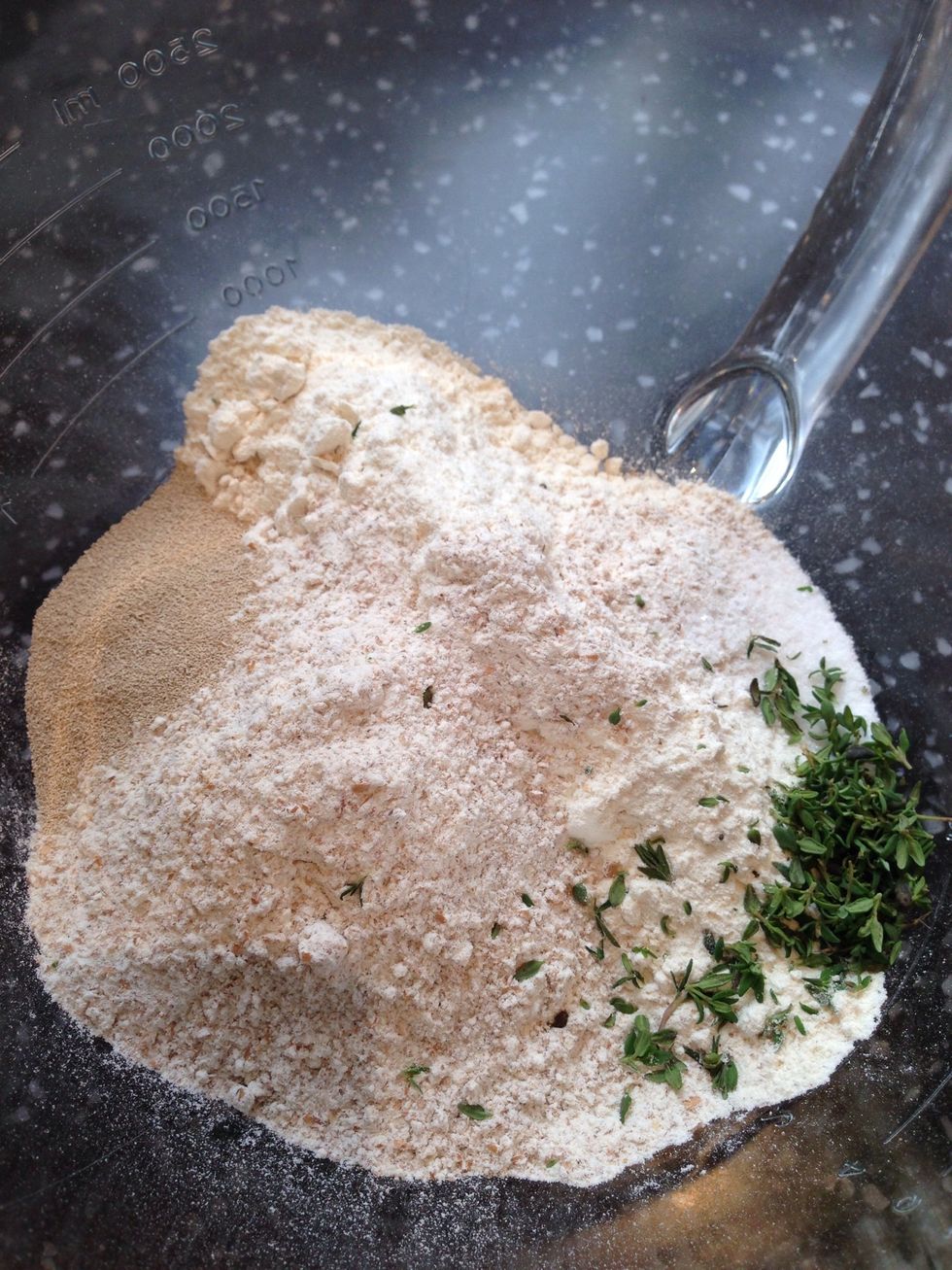 Add both flours, salt, yeast, and thyme into a bowl. Mix for 30 seconds then make a well In the centre of the flour mixture