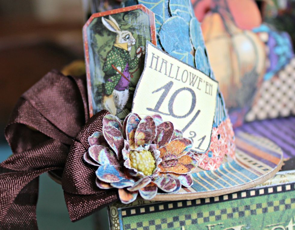 Add bow to side of hat along with a flower, chipboard, and image that has been cut from pattern paper.