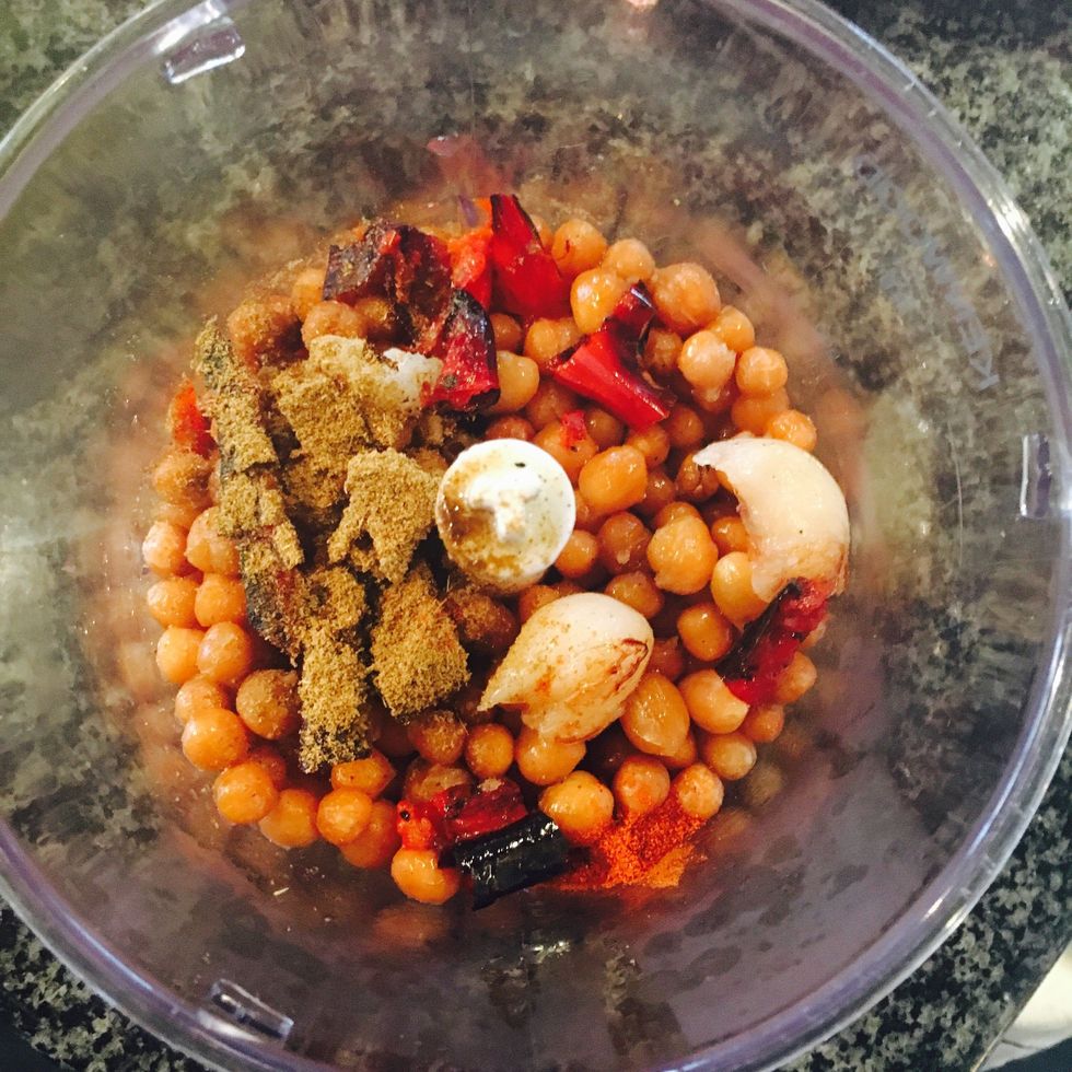 Add, chickpeas, 2tbs of olive oil, juice of the lemon, cumin, pinch of salt, chili and garlic (squeeze garlic clove out from the peel) to your blender.