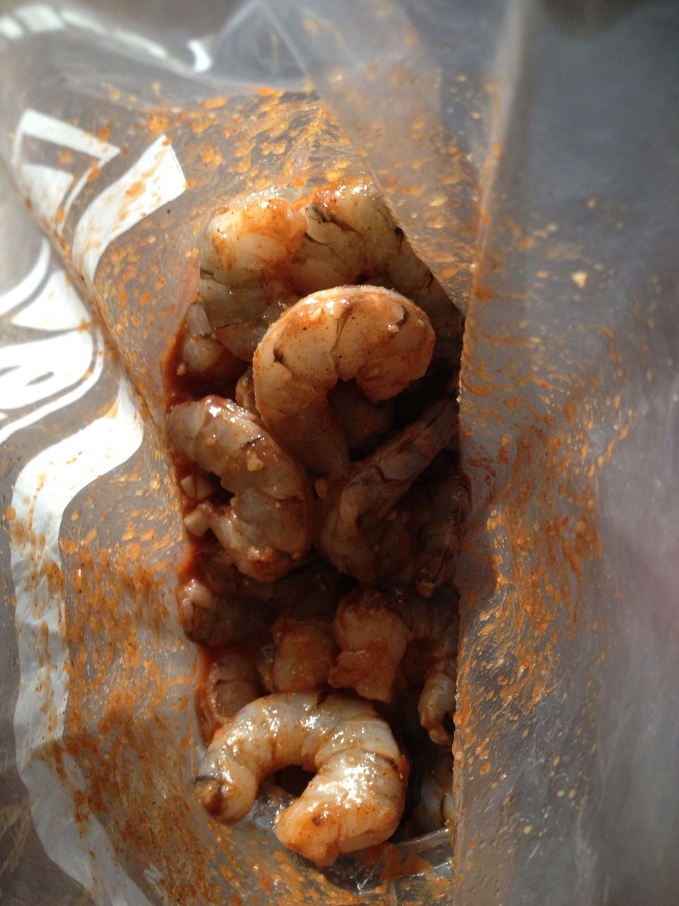 Add chopped garlic, sriracha sauce, 2 tbsp of oil, and shrimp to plastic resealable bag. Mix well and leave to marinate in fridge for at least one hour.
