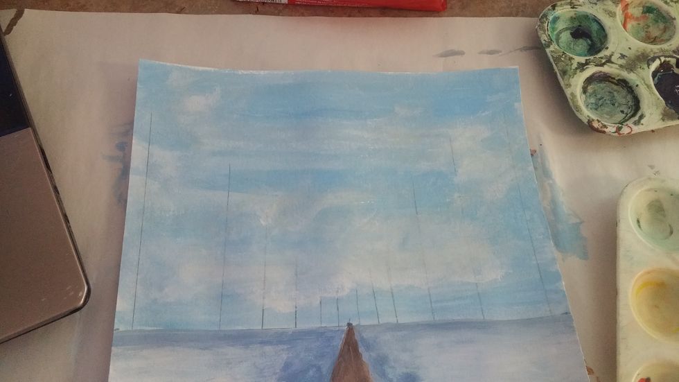 Add clouds with white paint while the blue is still wet. Blend well and make the clouds wispy.