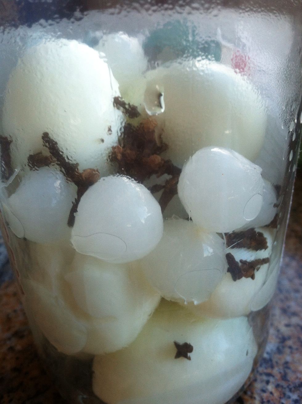 Add cloves and 6-8 pickled pearl onions to the eggs in the jar.