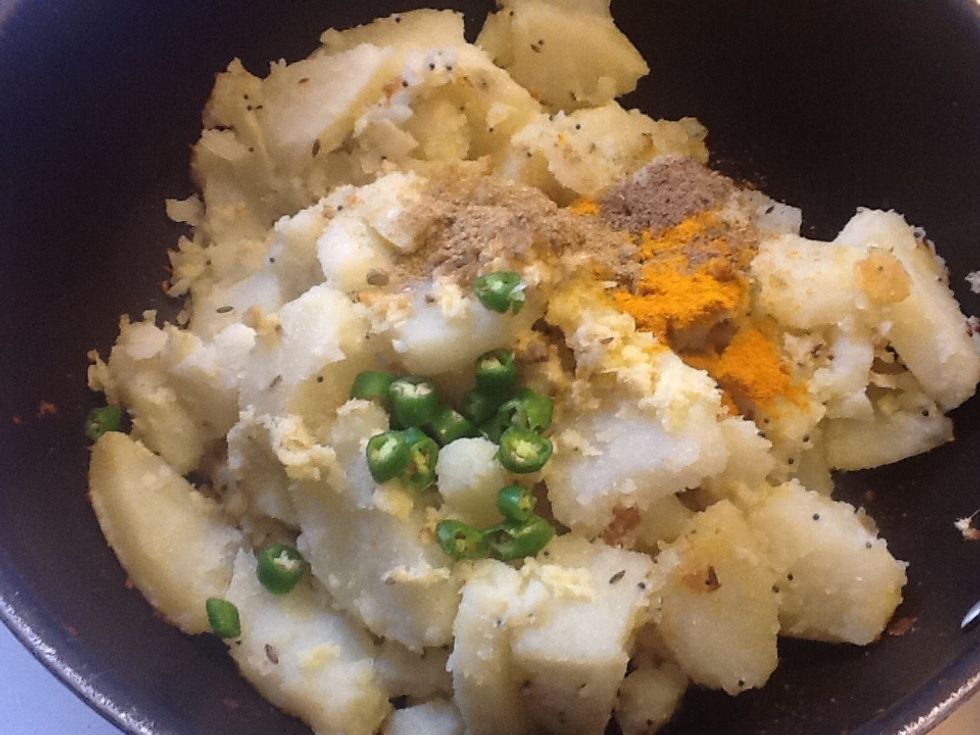 Add cubed potatoes, chopped green chillies, turmeric powder, coriander powder, salt , red chili powder, ginger paste and mix all of them (keep the gas on medium)