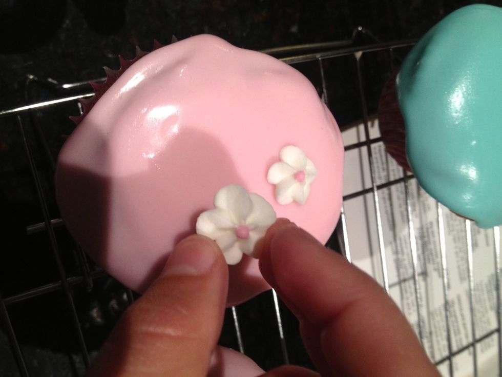 Add edible flower pieces around the cupcake (bought from supermarket or cake supplies store), ensuring to leave a space at opposite ends of the cupcake for the licorice handle