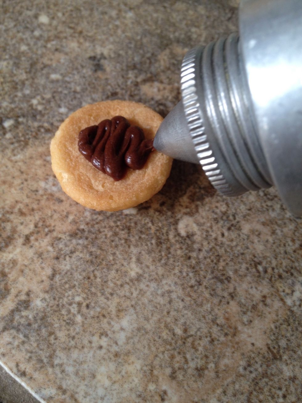 Add frosting to the bottom of a Nilla wafer. I like to use my cookie decorator to apply frosting...makes it very neat and simple!