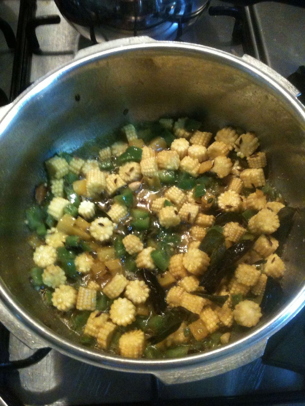 Add green chili, green pepper, yellow pepper, and baby corn. Mix well.