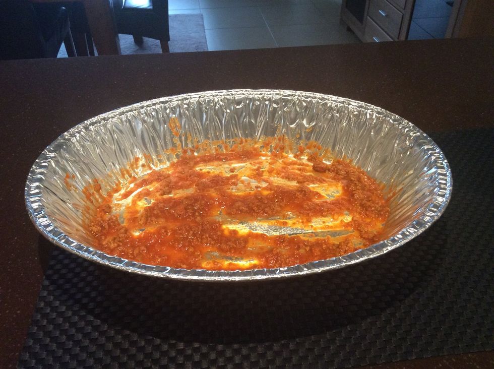 Add half ladle-size portion of sauce to the bottom of the tray.  Spread evenly.