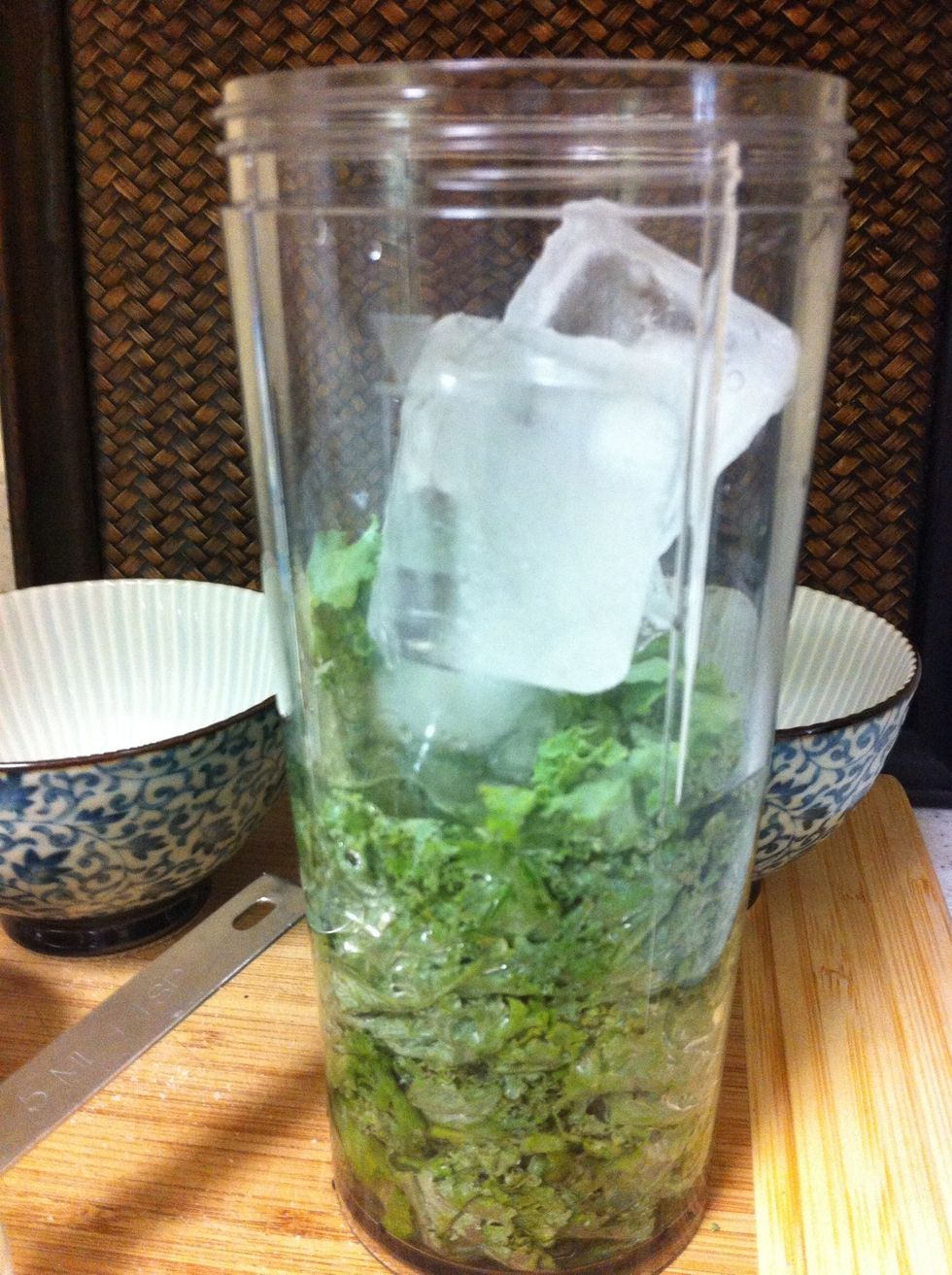 Add ice, water and kale or spinach to blender. I'm using an individual cup-type blender. Blend on high really well to break up the greens.