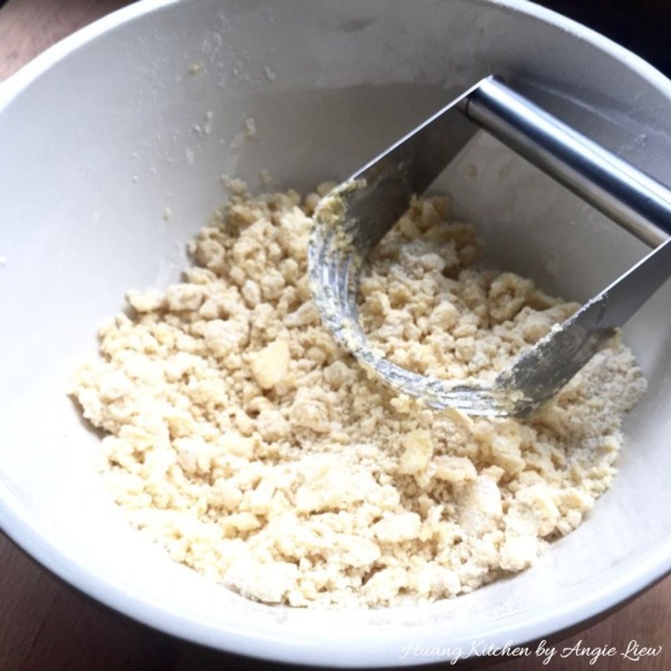 Add in COLD diced butter cubes. Then using a pastry cutter, cut the cold butter into the flour mixture until mixture resembles fine bread crumbs. This is to create flaky layers in the pineapple tarts.